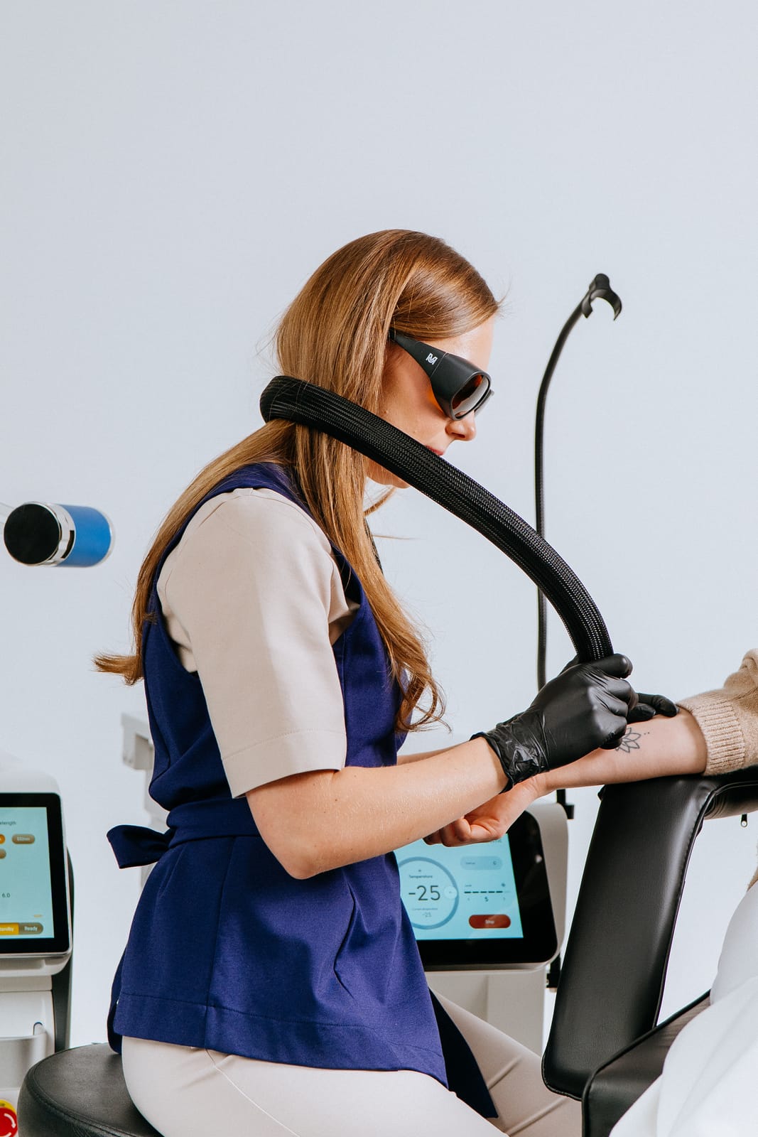 A specialist in protective glasses working with a laser on a client’s arm